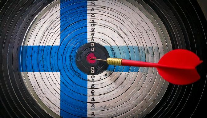 En bild av en piltavla i den finska flaggans färger och en pil som träffat i mitten. Illustrerar översättning till finska.